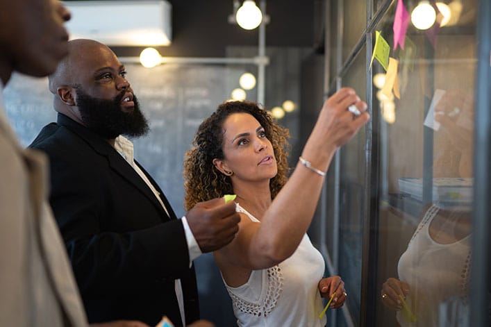 BOL-GettyImages-1132754790 Organizational leaders putting sticky notes on a board.