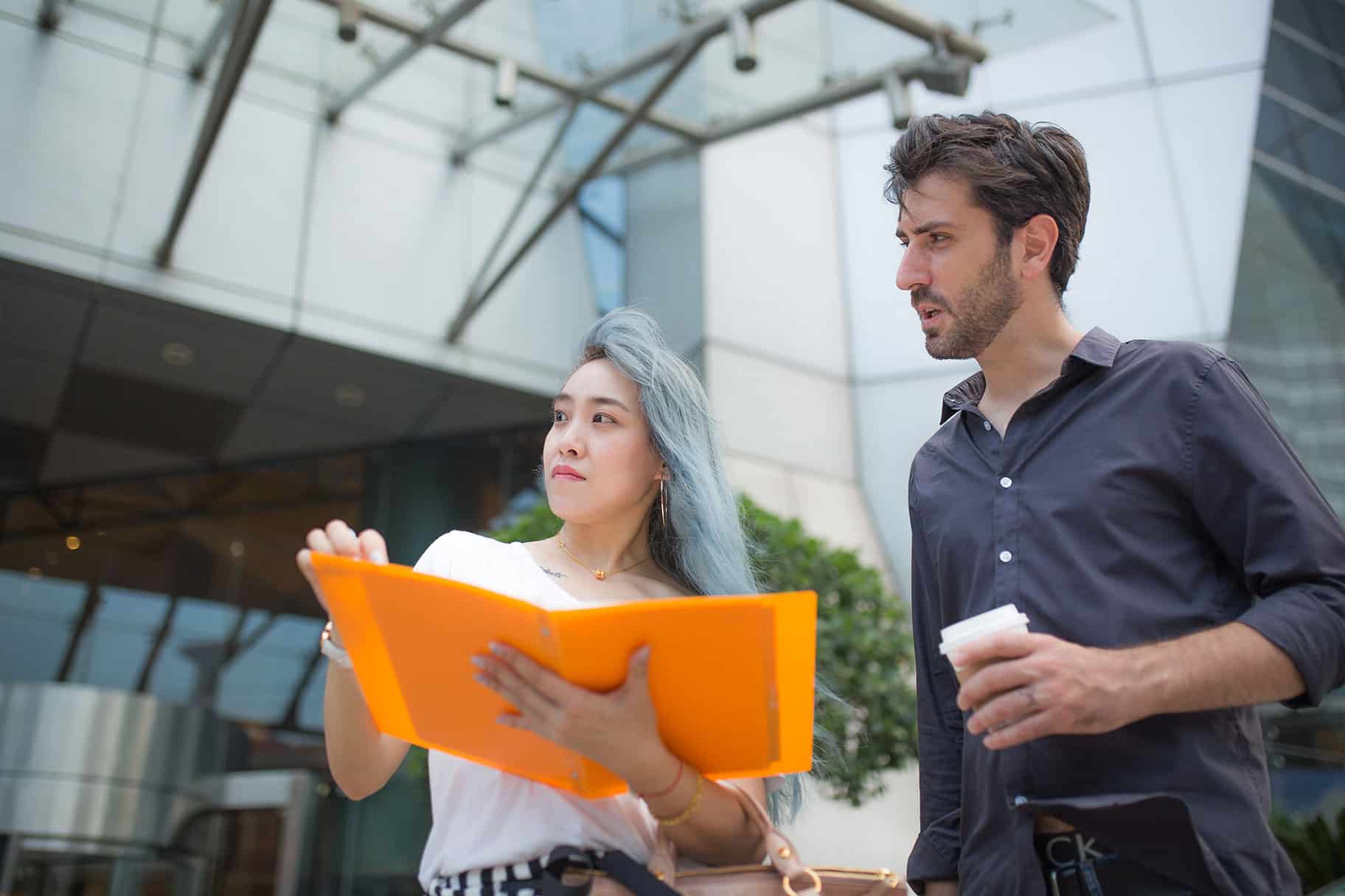 Sustainability professionals holding a folder and a beverage standing in a building.