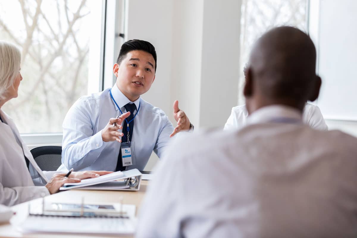 A healthcare administrator in a meeting with other professionals.