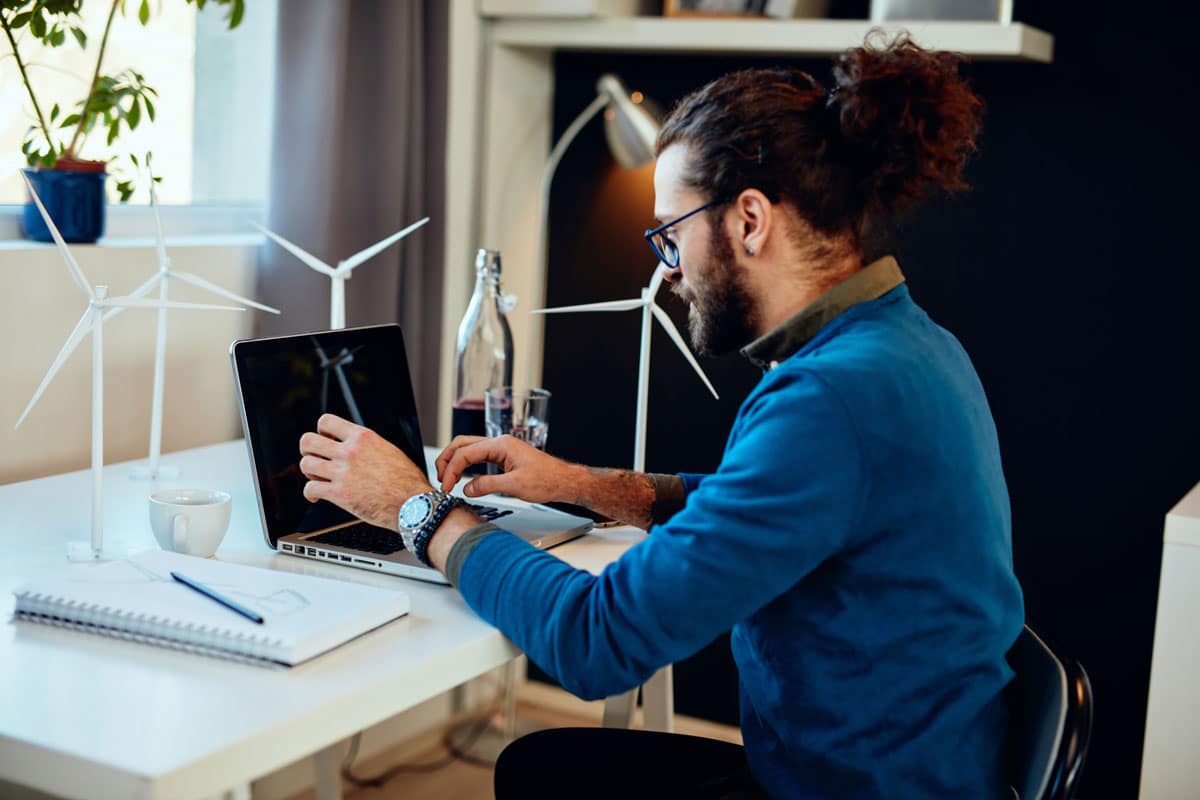 A social entrepreneur works at a laptop next to models of wind turbines.