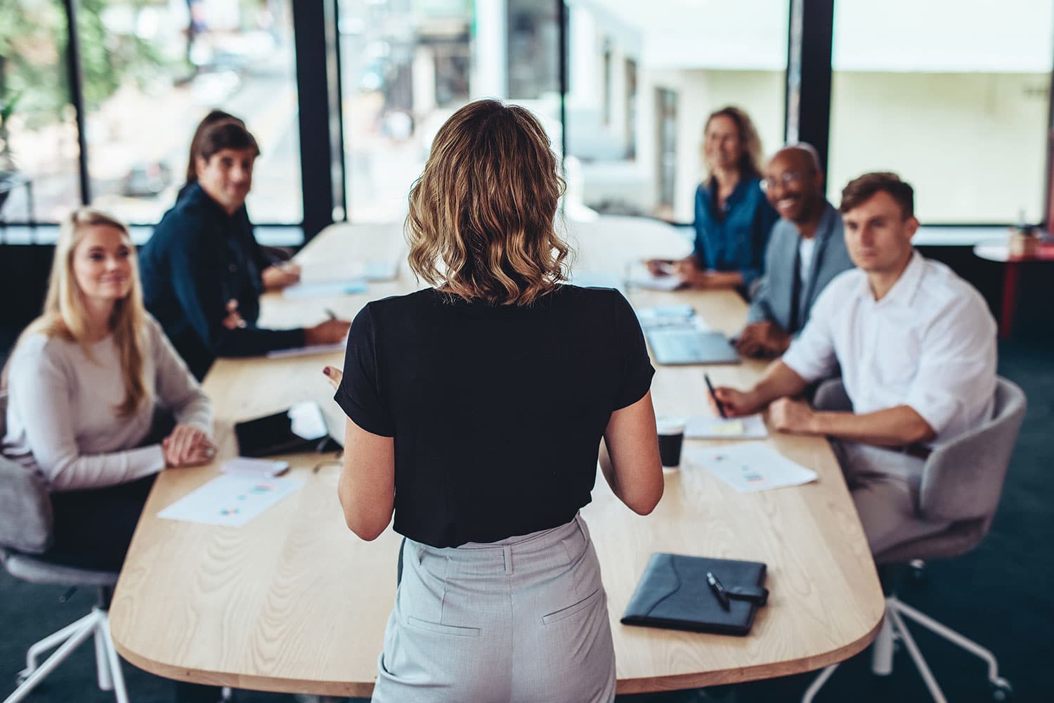 A business leader standing in a conference room speaks to a small team.