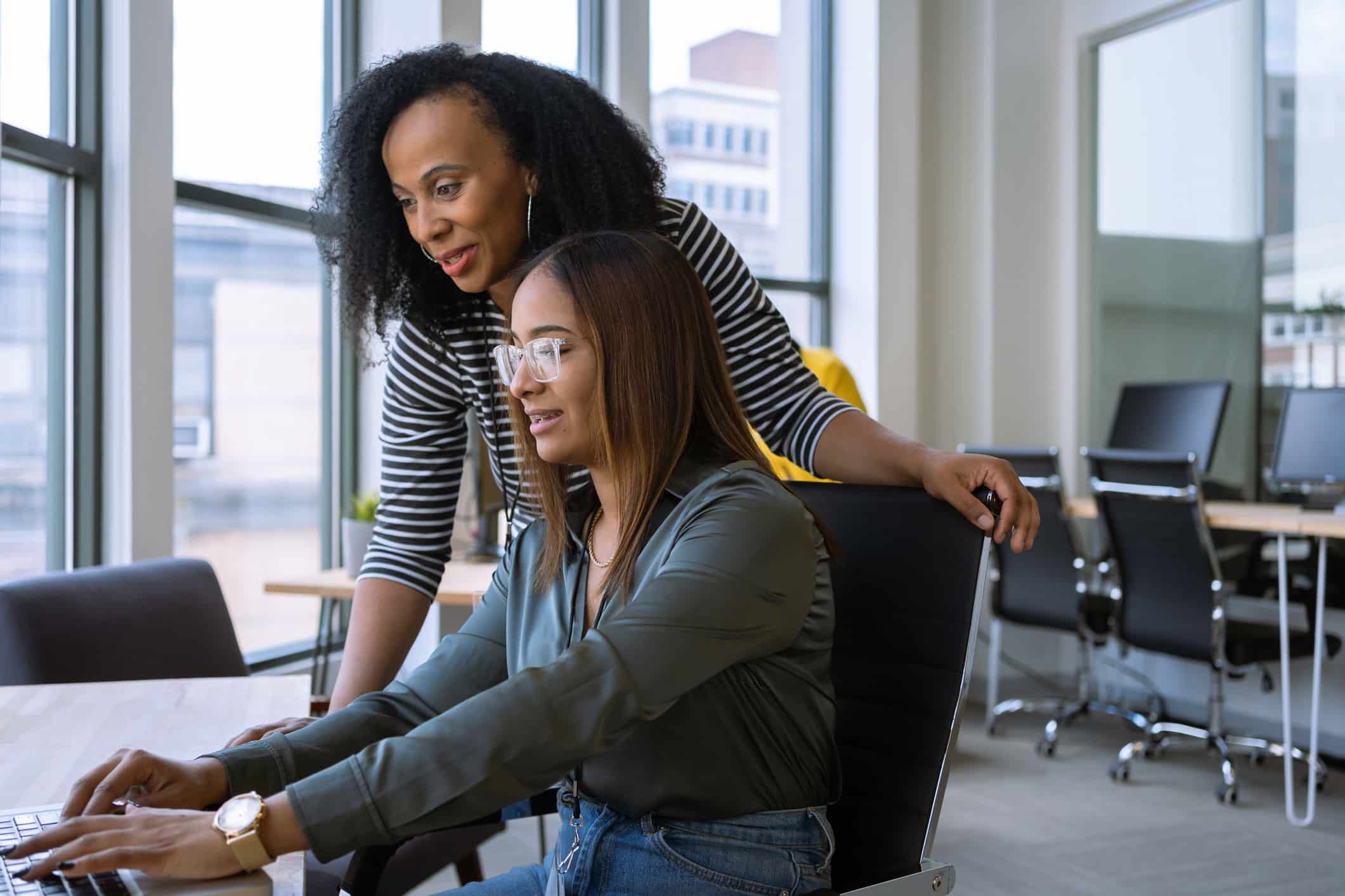 GettyImages-1398577959 A team leader observes over an employee’s shoulder while they work on a computer.