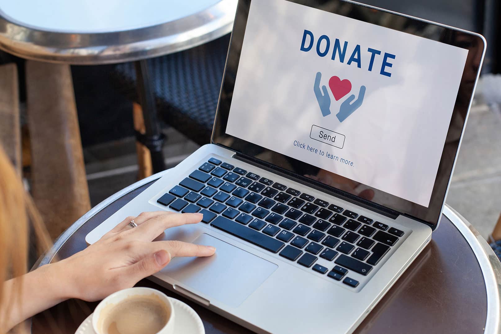 A person in a cafe uses a laptop displaying “Donate.”