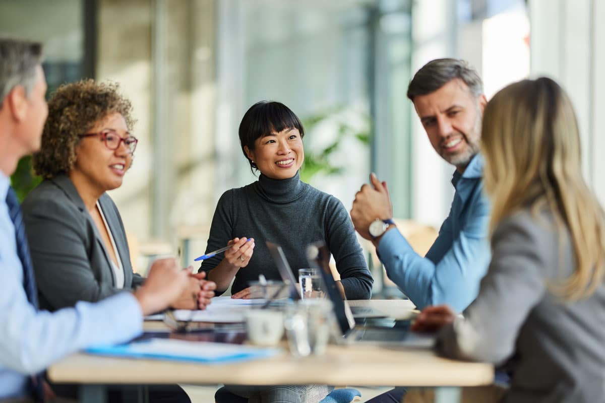 A nonprofit program manager leads a team meeting around a conference table.
