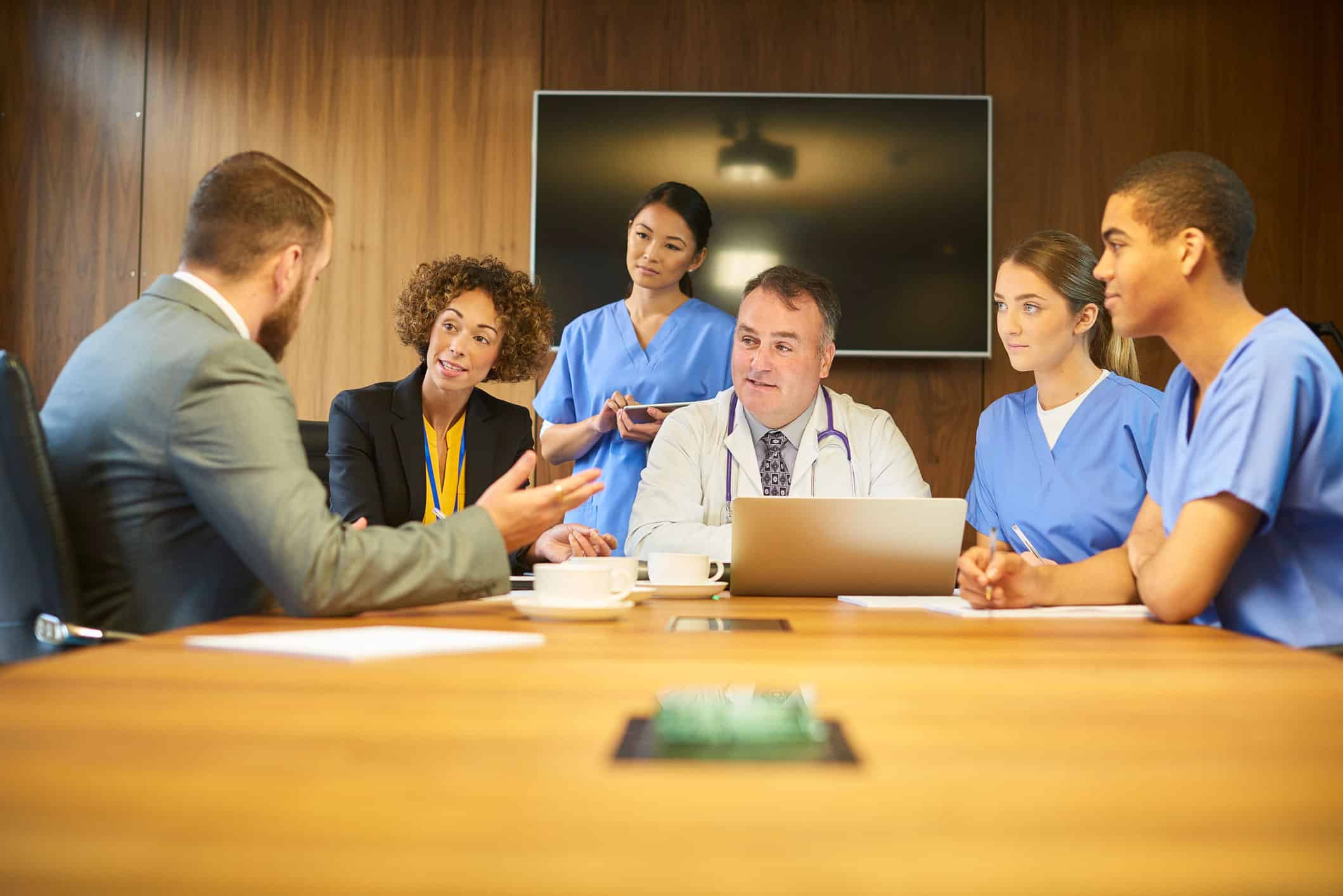 GettyImages-600155274 Healthcare administrators meet with clinicians around a conference table.