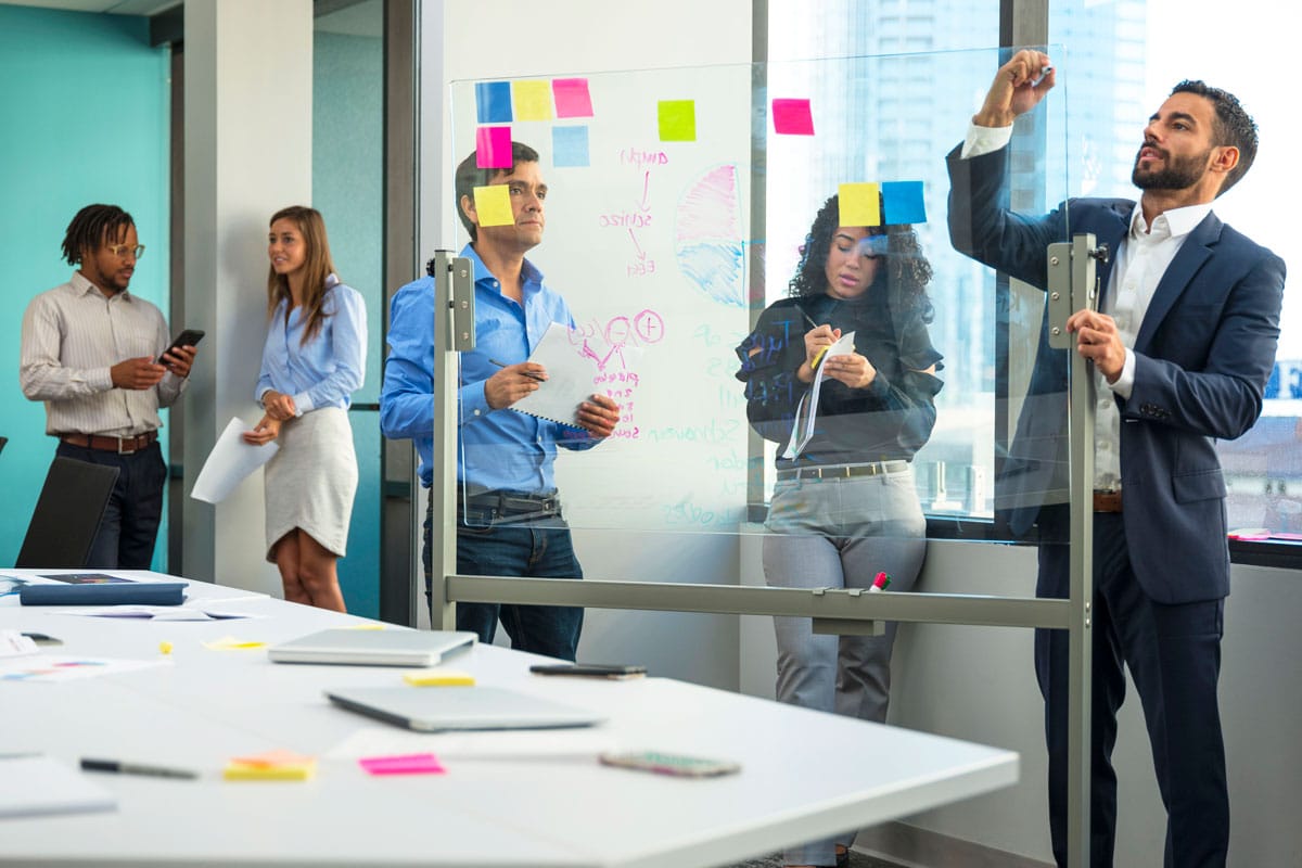 A project manager writing on a board in an office.