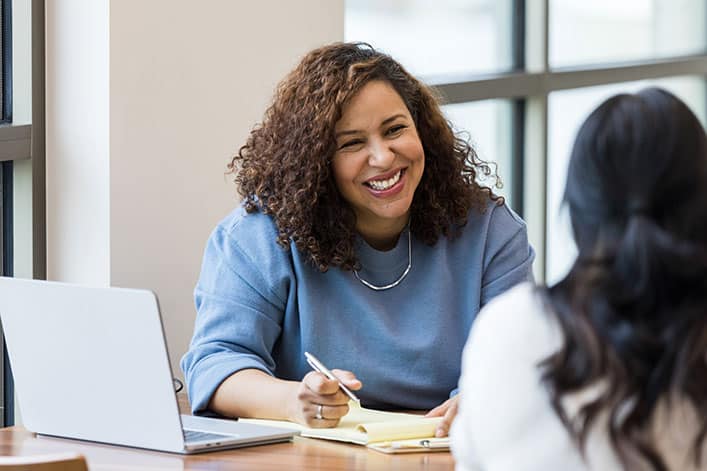 A smiling human resources professional interviews a potential new hire.