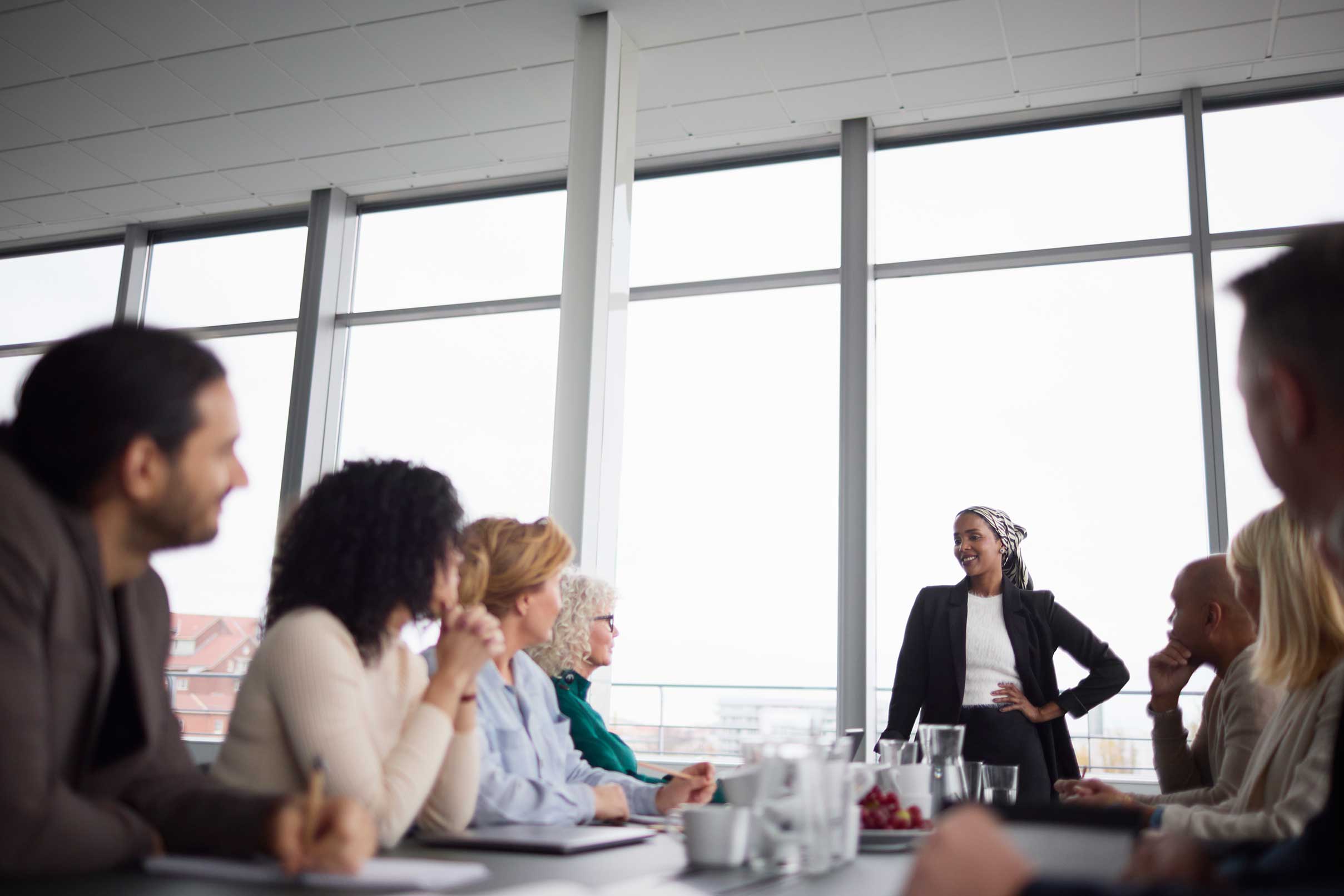 Master’s in Organizational Leadership: Human Resources Degree Online a woman standing at the end of a table speaking to a seated group of people