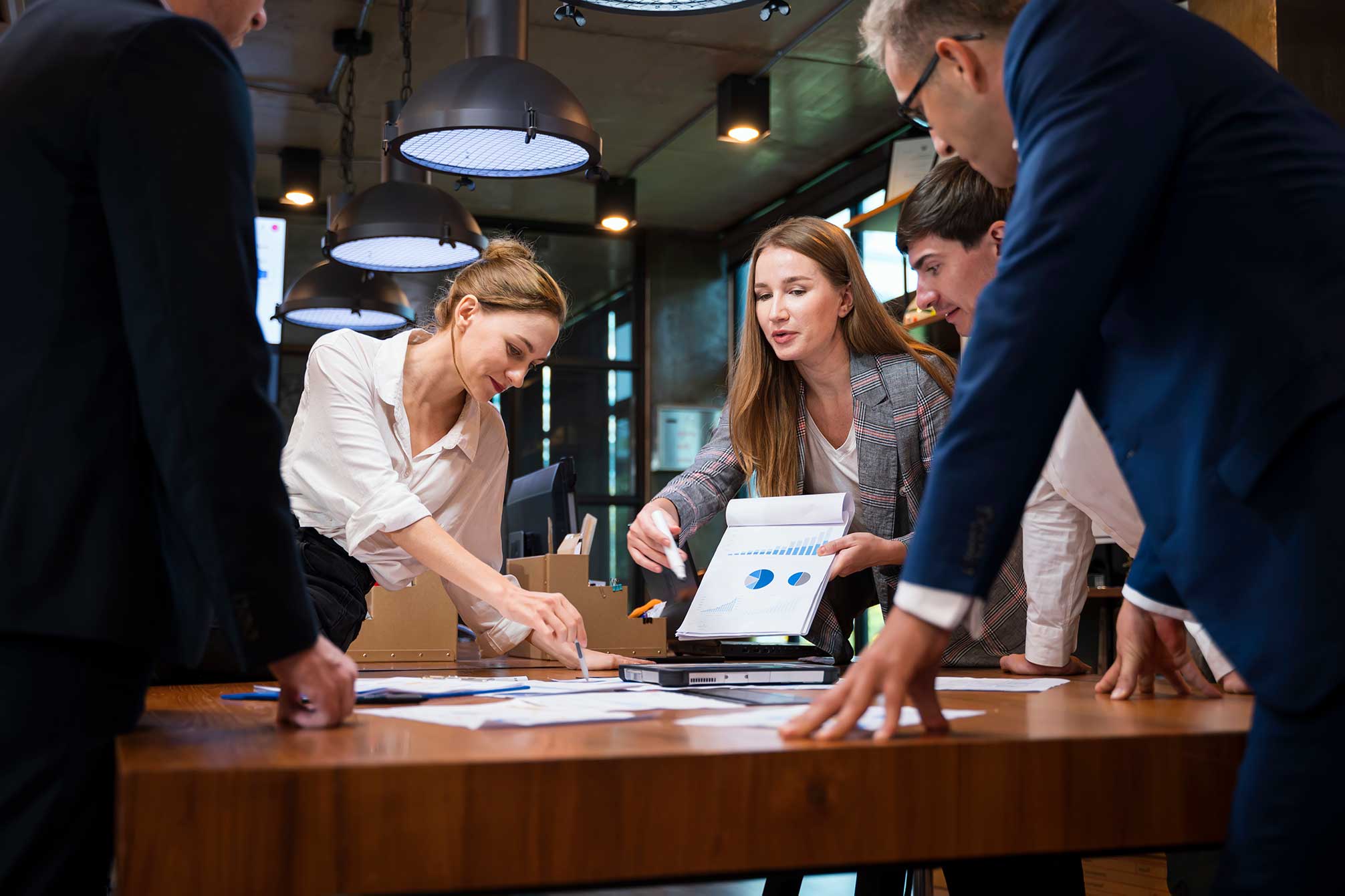 Master of arts in Organizational Leadership: Management Online five people standing around a desk working together to complete a project